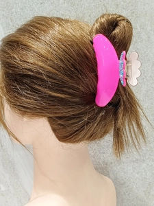 Detail view of pink acetic acid hair claw clip with crystal rhinestones on long hair