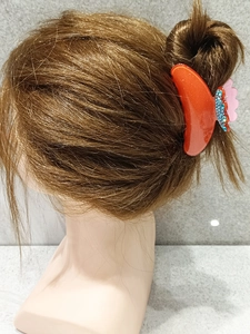 Detail view of acetate hair claw clip with rhinestones shown on a hair bun