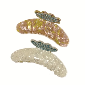 Large acetate hair claws with marble textures and blue rhinestones set on white background