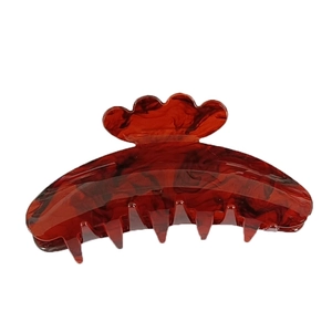 Close-up of a red-brown tortoiseshell hair claw clip with a wavy handle and polished finish