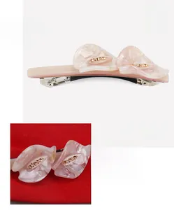 Makro-Detail einer eleganten rosa Acetat-Haarklammer mit champagnerfarbenen Strasssteinen