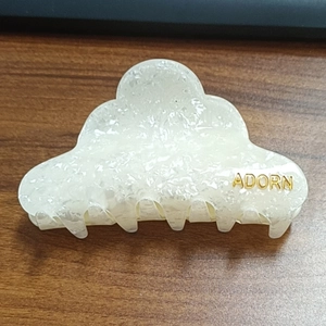 Vintage pearlescent cloud hair claw with gold ADORN letter on dark wooden table