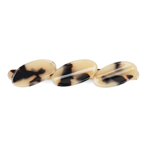 Close-up of three layered oval cream acetate hair clips with brown tortoiseshell pattern