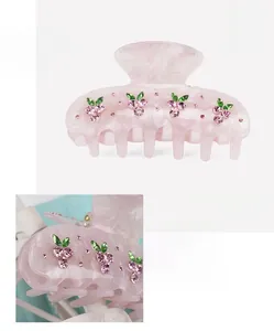 Detailed macro view of pink cellulose acetate hair claw with sparkling rhinestone cherries