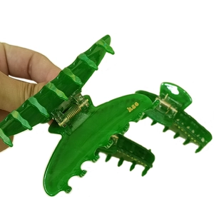 Pinza per capelli in acrilico verde con scritte dorate, vista laterale tenuta in mano