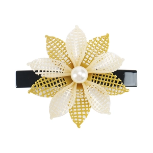 Detail of a floral hair clip with layered cream and ginger petals and a large center pearl