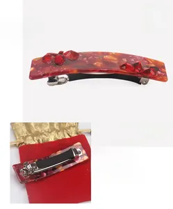 Detail view of large red cellulose acetate hair clip with floral crystal pattern