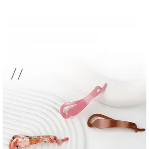 Vue détaillée de trois pinces à cheveux vintage en acétate rose, marron et à motifs