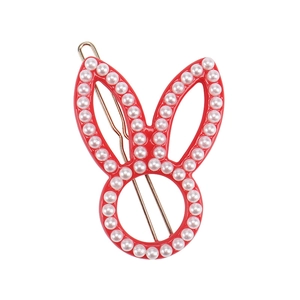 Close-up of a red rabbit hair clip with white pearls and gold metal accents on a white background