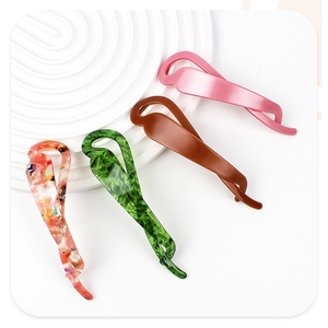Détail de quatre barrettes banane en acétate aux motifs marbre rose, vert et fleuri