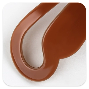 Détail macro de la texture en résine caramel lisse d'une pince à cheveux banane géométrique