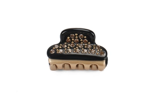 Close-up of a small black acetate hair claw clip with amber rhinestones and gold beads