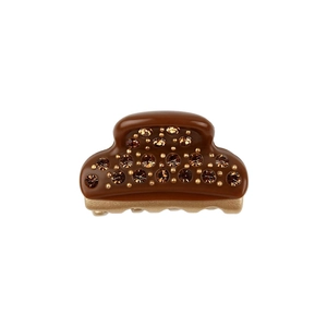 Close-up of mini acetate hair claw with amber crystals and gold base on white background