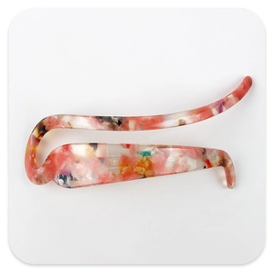 Détail de la barrette en acétate marbré rouge avec un design élégant en forme de S