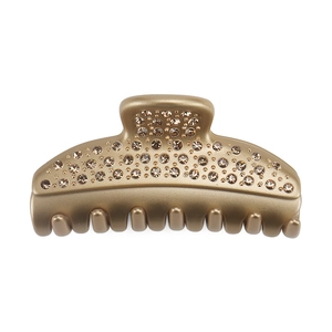 Macro detail of luxury matte gold hair claw clip with crystal pavé and rounded teeth