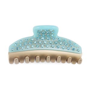 Detail of light blue crystal hair claw clip with golden rivets on acrylic base