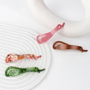 Barrettes banane en acétate aux motifs floraux et mats sur un plateau blanc chic