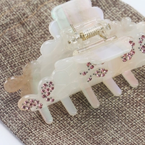 Détail de la pince à cheveux papillon avec strass roses sur acétate blanc perlé