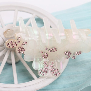 Vue macro de la pince à cheveux papillon nacrée avec des détails en strass roses