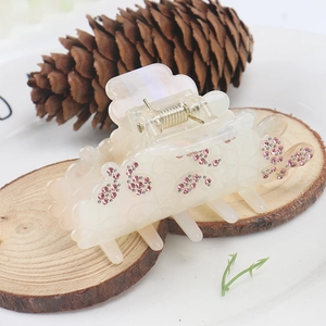 Détail d'une pince à cheveux en acétate crème avec papillon en strass rose sur bois