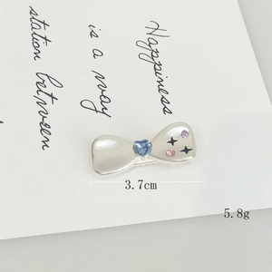 Dettaglio fermaglio a fiocco con zircone a cuore blu e cristalli viola, lungo 3.7cm