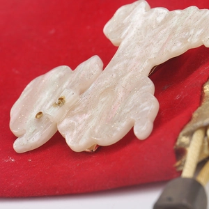 Macro shot of white pearlescent resin puppy hair clip on red velvet background