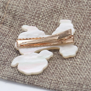 Close-up of golden metal duckbill hair clip with white marble texture acetate back