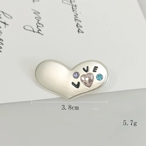 Dettaglio spilla a cuore argento con scritta LOVE e cristalli di zircone colorati