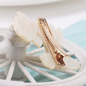 Detailed macro view of the cream white acrylic hair clip with its sturdy gold metal grip