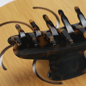 Detailed top view of a large tortoise shell hair claw clip on a wooden tray