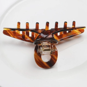 Detailed macro view of an amber cellulose acetate hair claw clip on a white tray