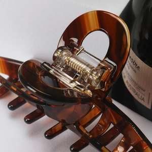 Close-up of tortoise shell hair claw clip with golden metal spring and glossy finish