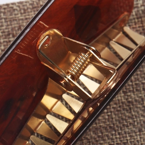 Macro shot of acetic acid hair claw with golden metal spring and tortoise texture