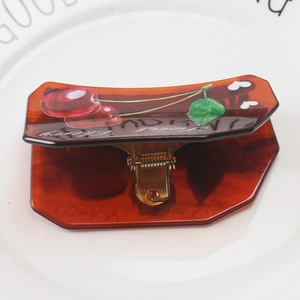 Close-up of amber acetate hair claw with red cherry print and Sweet Cherry lettering
