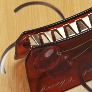 Detailed close-up of a tortoiseshell acetate hair claw featuring red cherry prints