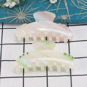 Detail of colorful acetate hair claws with iridescent texture and sparkling rhinestones