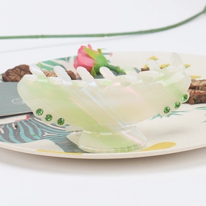 Detail of light green acetate hair claw clip with pearl luster and green rhinestones