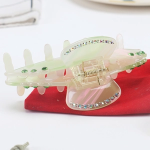 Gradient acetate hair claw clip with colorful rhinestones on a red velvet pouch