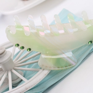 Detail of light green acetate claw clip with iridescent finish and green rhinestones