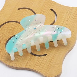 Detail view of large acetate claw clip with gradient green color and starry rhinestones