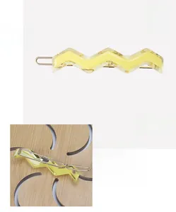 Detail view of a 5mm thick yellow acetate wavy hair clip with gold metal clamp