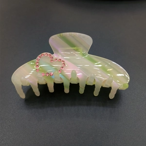 Detailed view of iridescent acetate hair claw with pink rhinestone heart patterns