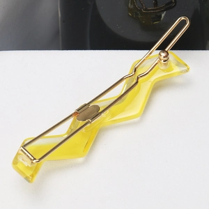 Detail of yellow acetate wavy hair clip with golden metal fastener on a clean background