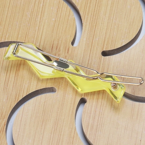 Macro detail of a bright yellow wavy lightning acetate hair clip with gold metal grip