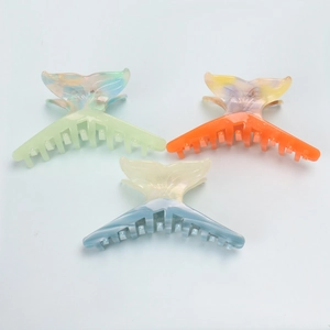 Detail of fishtail-shaped hair claws in green, orange, and blue with marble texture