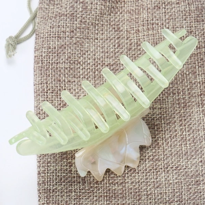 Détail d'une pince à cheveux en acétate bicolore vert et blanc avec effet marbré poli