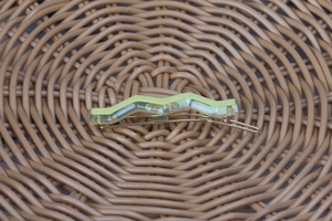 Close-up of wavy yellow acetate hair clip with transparent layers and gold metal base