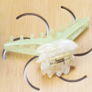 Détail de la pince à cheveux lotus en acétate vert clair avec texture marbrée et ressort