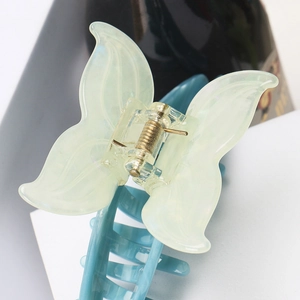 Detailed macro view of butterfly hair claw clip with green acetate wings and blue base