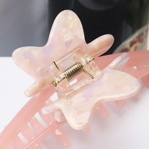 Macro shot of durable metal spring hinge and pink marbled acetate butterfly hair claw clip